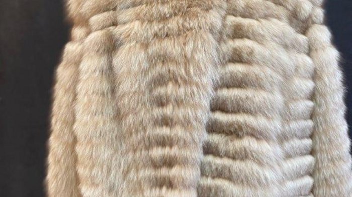 Pellicciai Cappotto di pelliccia beige su manichino con sfondo scuro