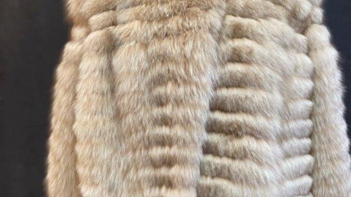 Pellicciai Cappotto di pelliccia beige su manichino con sfondo scuro