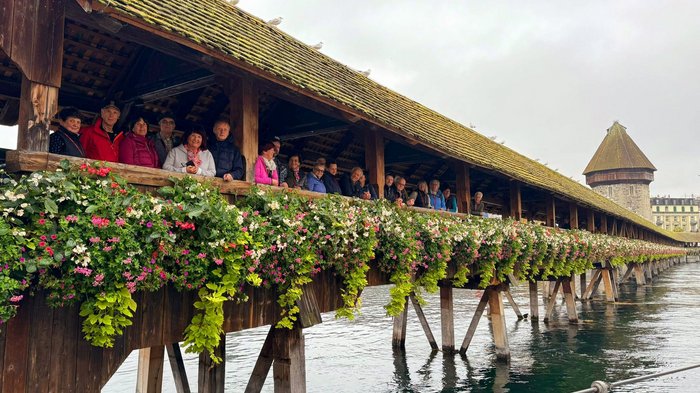 Viaggio autunnale degli artigiani anziani di lvh.apa: puro divertimento e panorama svizzero Persone sul ponte coperto storico con fiori a Lucerna