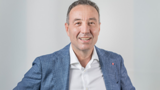 News Ritratto di uomo sorridente con giacca blu su sfondo neutro
