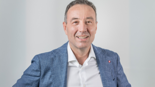 News Ritratto di uomo sorridente con giacca blu su sfondo neutro