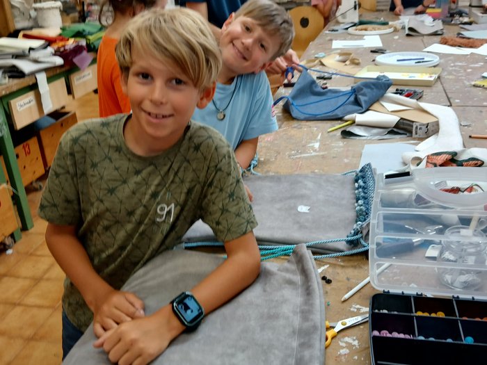 Mit Faden, Fantasie und Fingerfertigkeit – Die KidsAcademy in Brixen macht Handwerk erlebbar Kinder bei einem Bastelworkshop an einem Tisch mit Stoff und Werkzeugen