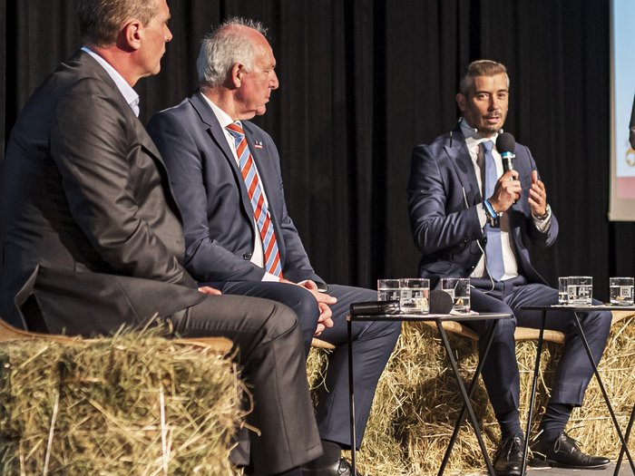 Tag des Handwerks - Jugend als Schlüssel für unsere Zukunft Diskussion mit drei Männern in Anzügen auf Strohballen sitzend bei einem Event