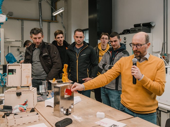© MakerSpace, lvh.apa, Fiorentino Mann erklärt makergerechtes Projekt vor mehreren Zuschauern in Werkstatt