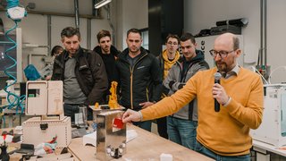 © MakerSpace, lvh.apa, Fiorentino Mann erklärt makergerechtes Projekt vor mehreren Zuschauern in Werkstatt