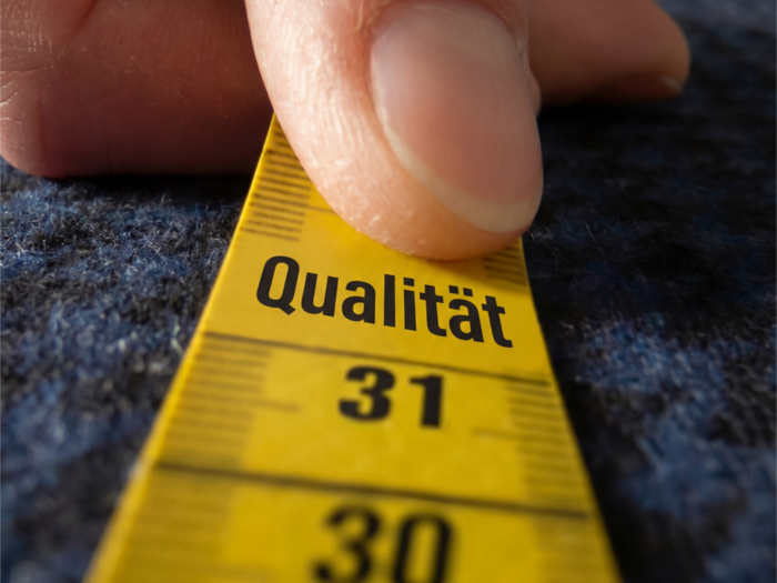 Qualità, individualità e benessere Mano che misura la qualità con un metro giallo su sfondo blu